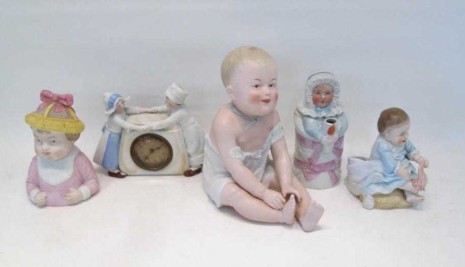 Appraisal: FIVE BISQUE FIGURINES including a seated piano baby H a