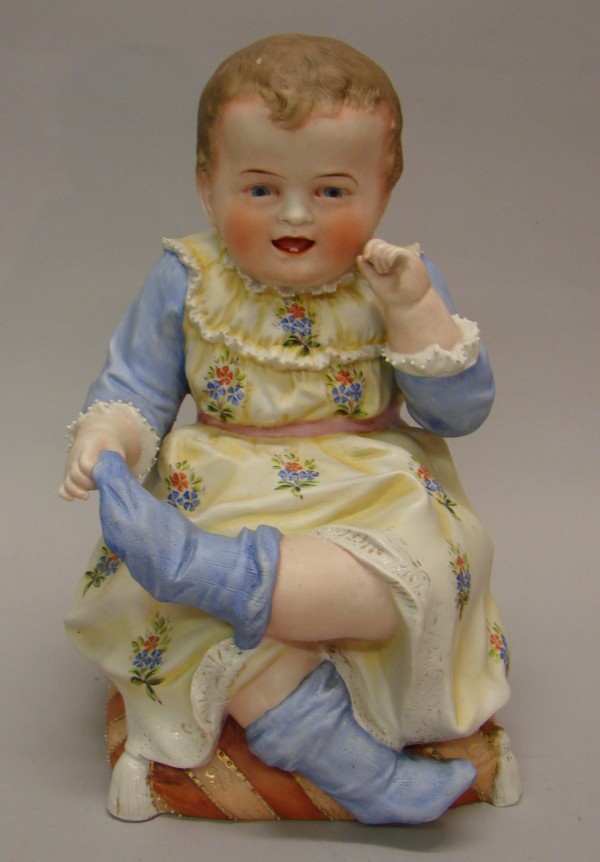 Appraisal: Bisque piano baby figurine Child sitting on pillow pulling off