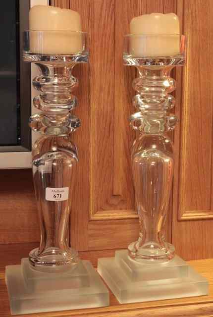 Appraisal: A PAIR OF GLASS TURNED CANDLESTICKS on a stepped plinth