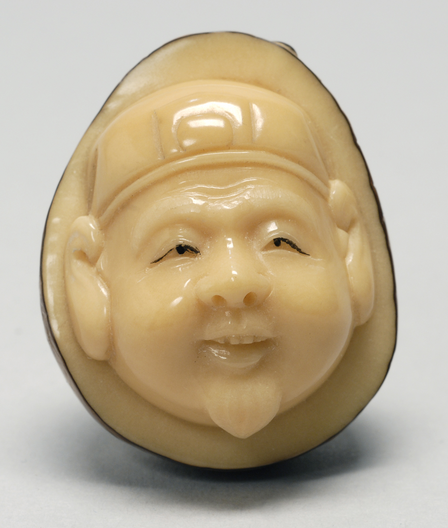 Appraisal: CARVED TAGUA NUT NETSUKE Early th CenturyA man's face emerging