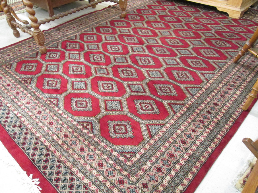 Appraisal: HAND KNOTTED RED FIELD BOKHARA CARPET India or Pakistan repeating