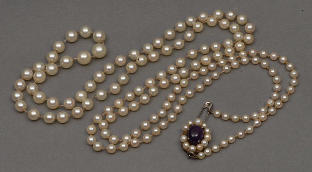 Appraisal: A GRADUATED CULTURED PEARL NECKLACE with amethyst coloured clasp long