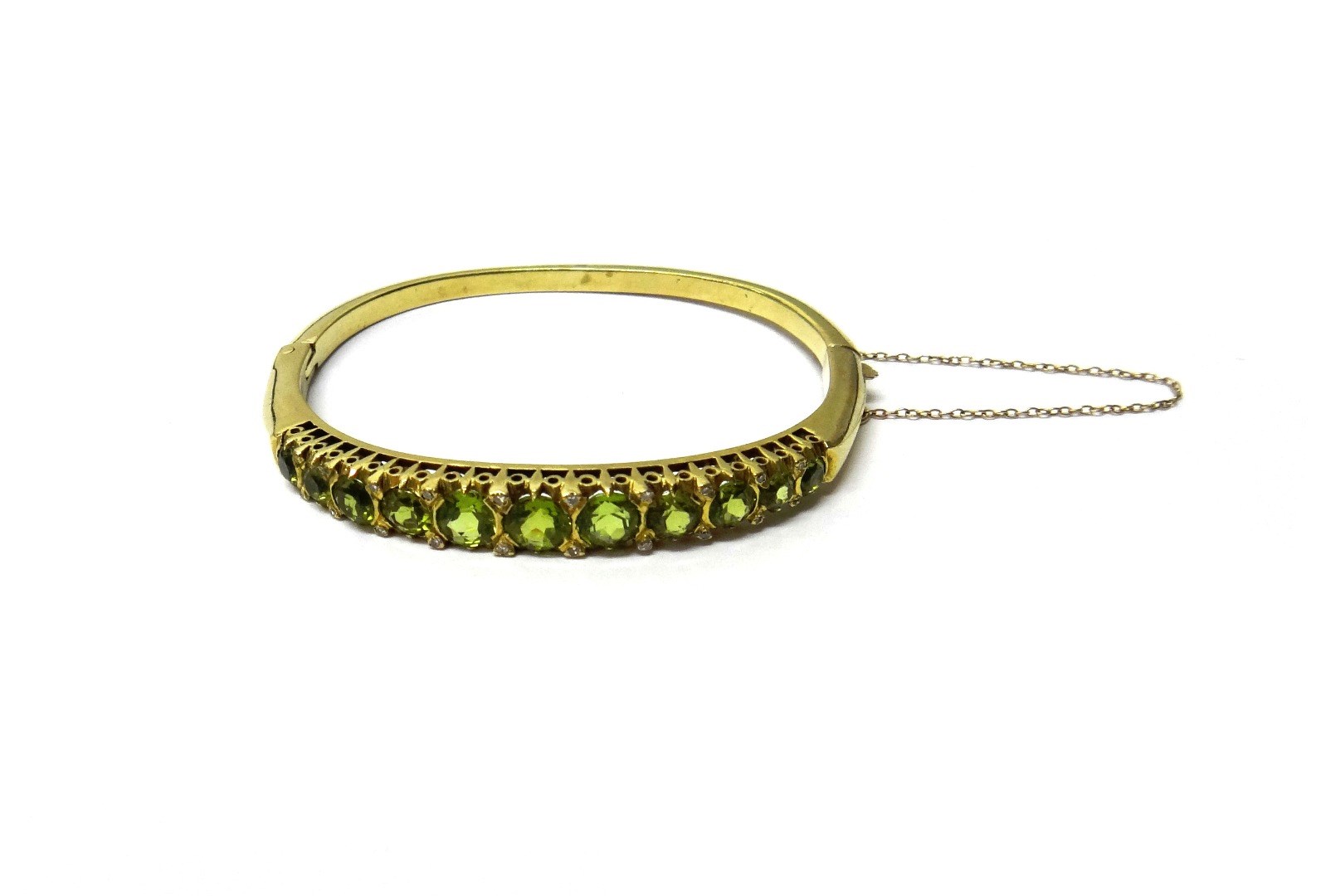 Appraisal: A ct gold peridot and diamond set oval hinged bangle