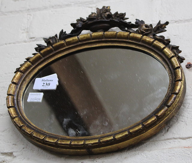 Appraisal: A REGENCY GILTWOOD MINIATURE OVAL HANGING WALL MIRROR with carved