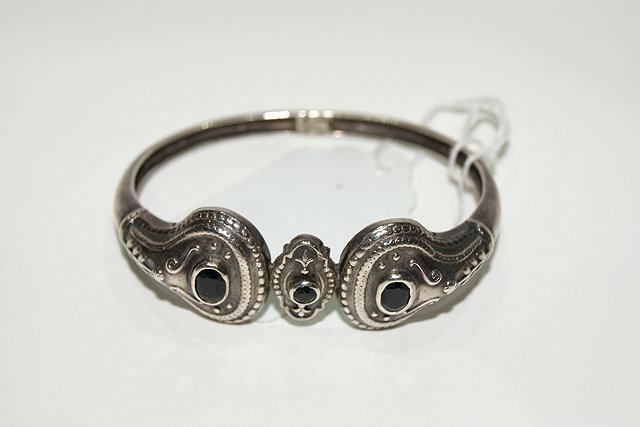 Appraisal: A GREEK SILVER BANGLE with relief stylised form with blue