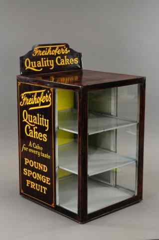 Appraisal: FREIHOFER'S CAKE DISPLAY CASE Lithographed tin three shelf glass panel