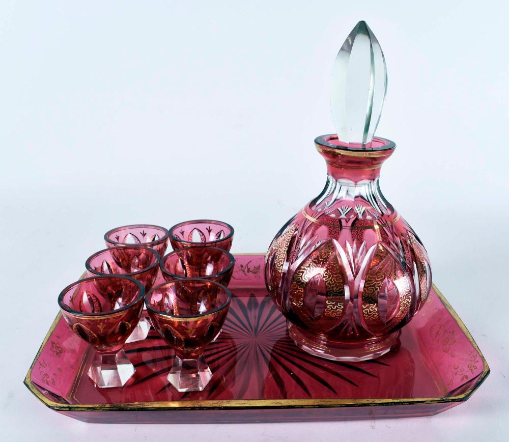 Appraisal: CONTINENTAL GILT RUBY GLASS DECANTER CORDIALS TRAYCirca The spherical decanter