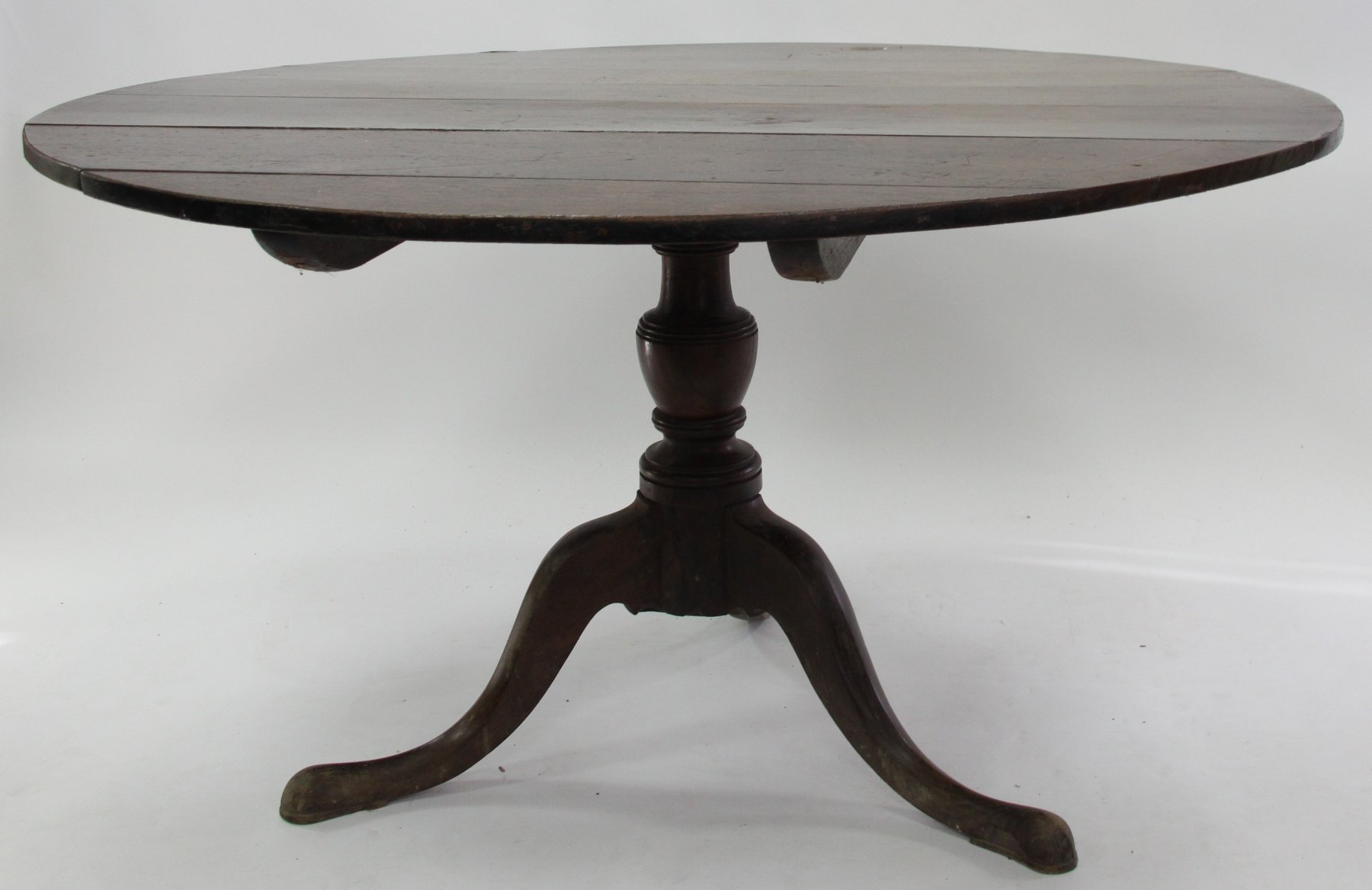 Appraisal: An oak tripod table the circular top on a baluster