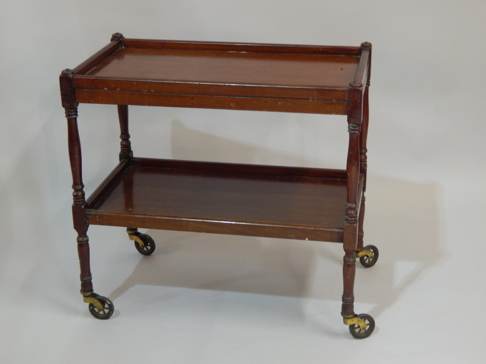 Appraisal: A mahogany two tier trolley with a slide section to