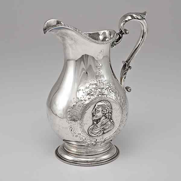 Appraisal: Silver-Plated Pitcher A silver-plated pitcher featuring two colonial men in