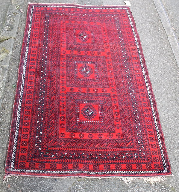 Appraisal: AN AFGHAN RED GROUND RUG with geometric decoration and running