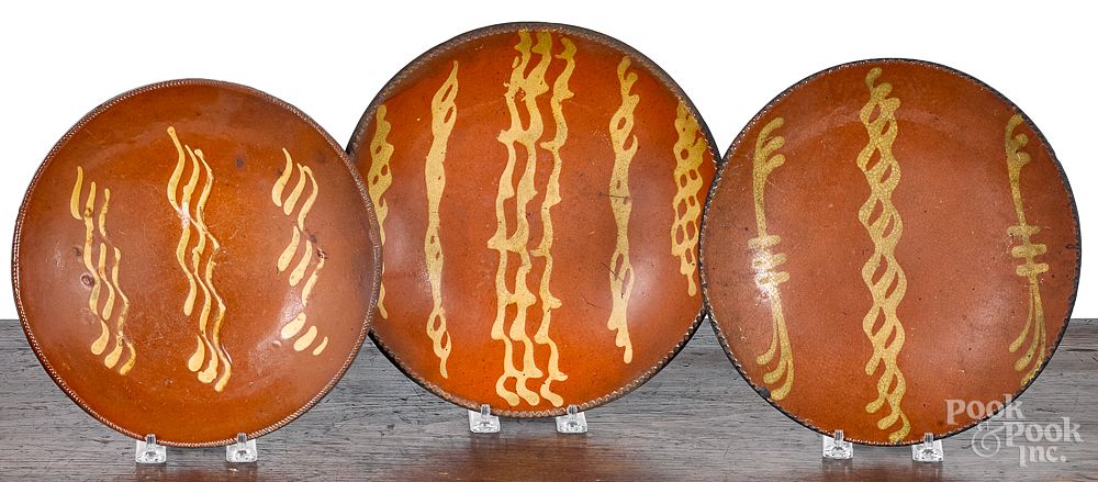 Appraisal: Three Pennsylvania slip decorated redware plates Three Pennsylvania slip decorated