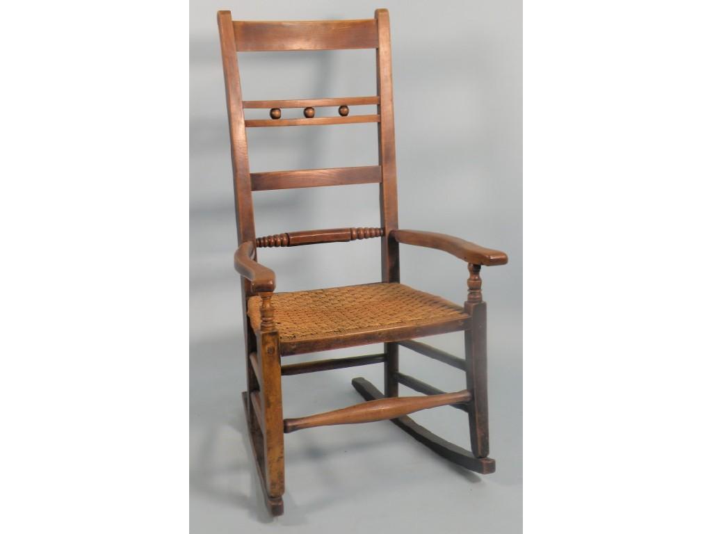 Appraisal: A thC fruitwood rocking chair with a bar back rush