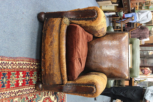 Appraisal: AN OLD LEATHER UPHOLSTERED CLUB ARMCHAIR standing on bun feet