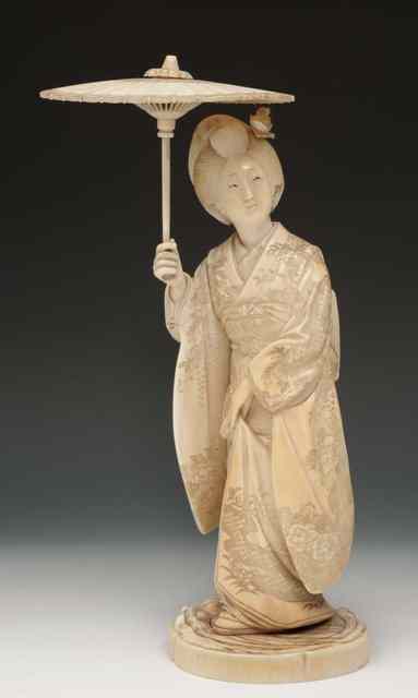 Appraisal: A JAPANESE IVORY OKIMONO of a standing courtesan holding an