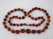 Appraisal: A graduated dark amber bead necklace with natural insect inclusions