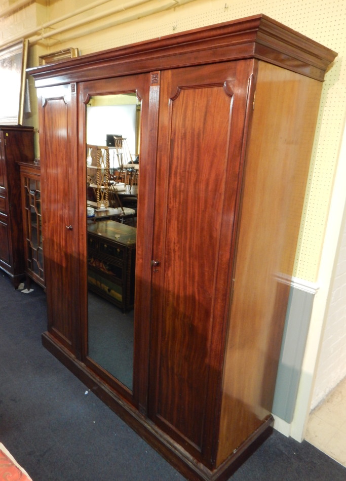 Appraisal: A Victorian mahogany triple wardrobe with a central mirror door