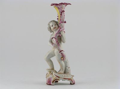 Appraisal: A Berlin candlestick modelled as a putto holding up a