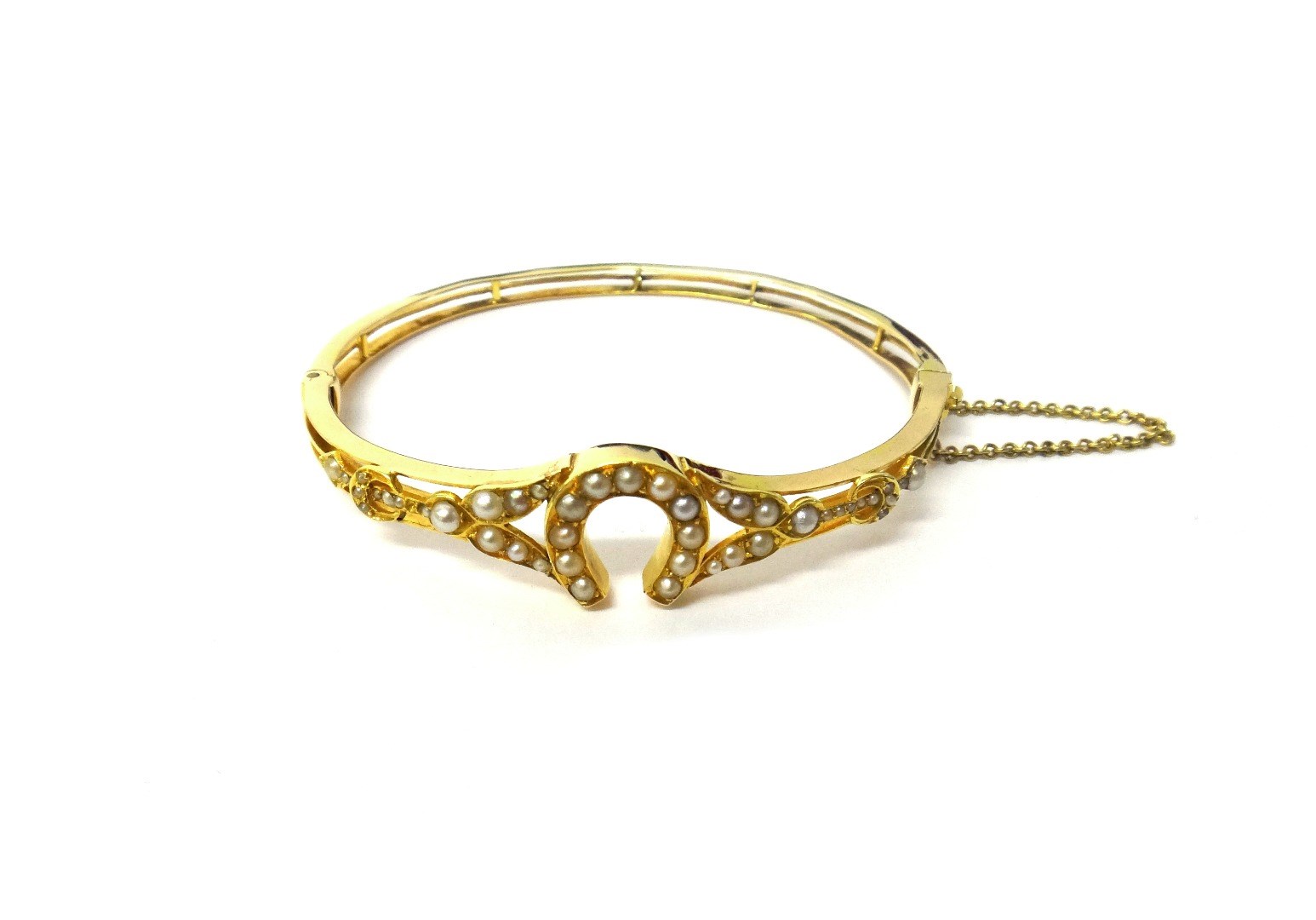 Appraisal: A gold and seed pearl set oval hinged bangle having