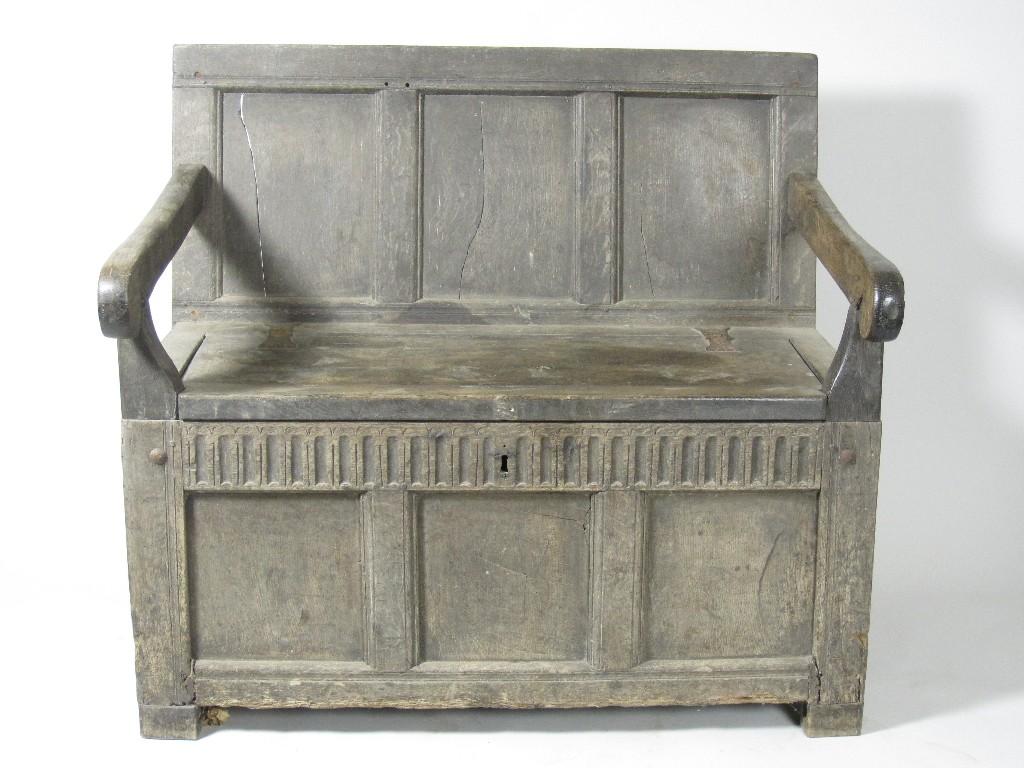 Appraisal: An antique oak panelled Settle with hinged lid scroll arms