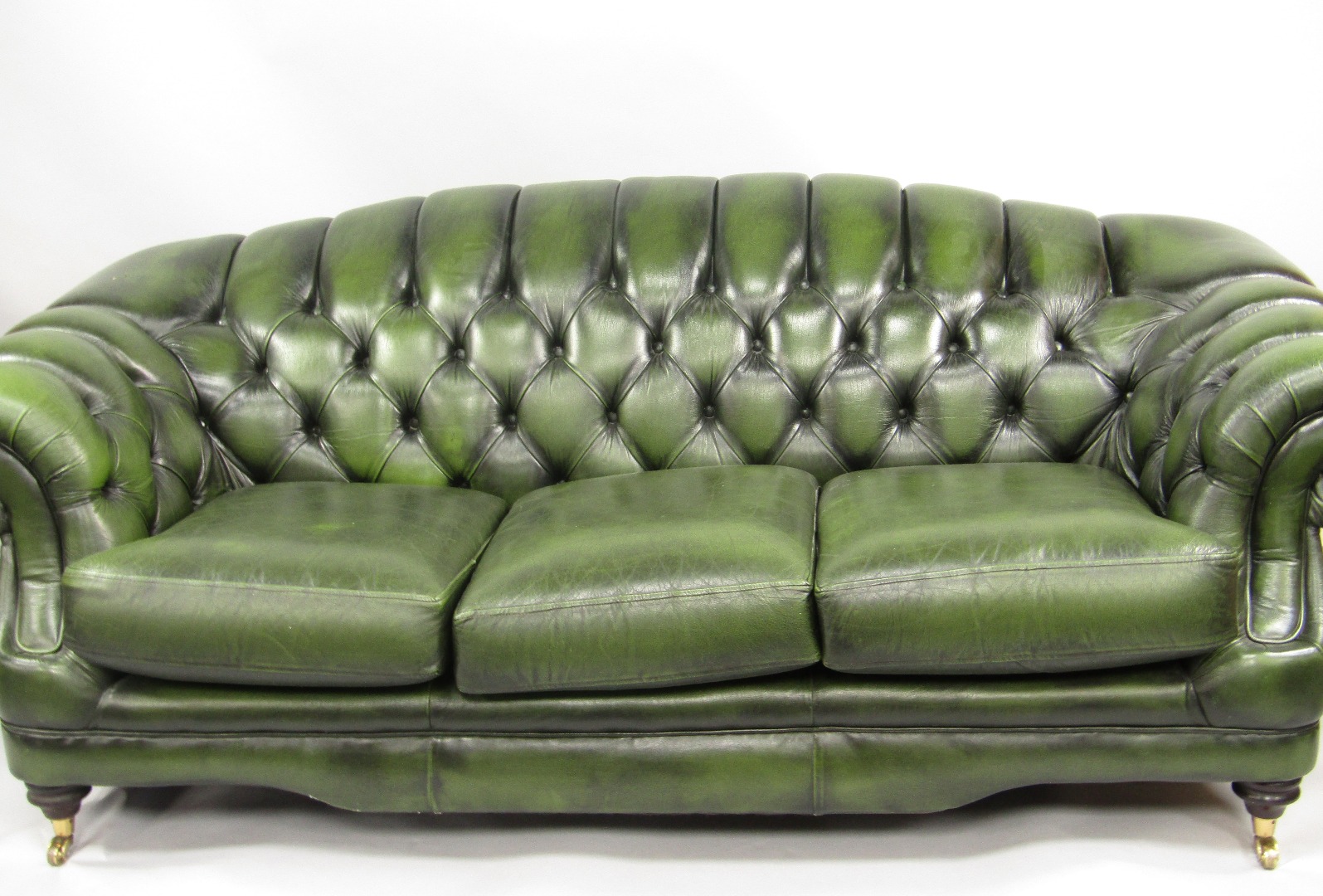 Appraisal: A green buttoned leather scroll sofa armchair and stool