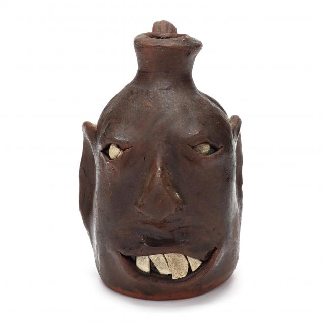 Appraisal: SOUTHERN SMALL FACE JUG Alkaline glazed stoneware over reddish clay