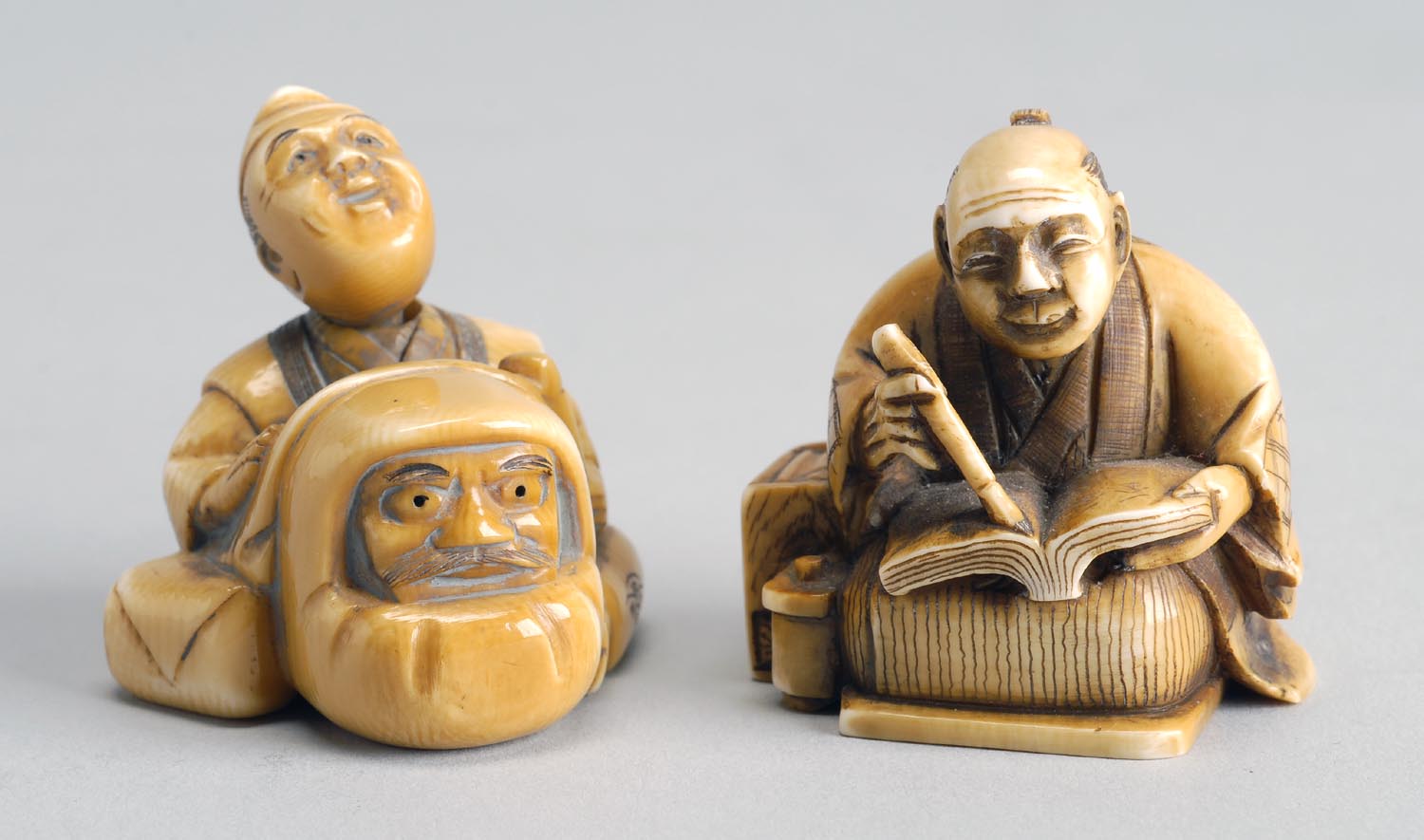 Appraisal: TWO IVORY NETSUKE A man reading from a book and