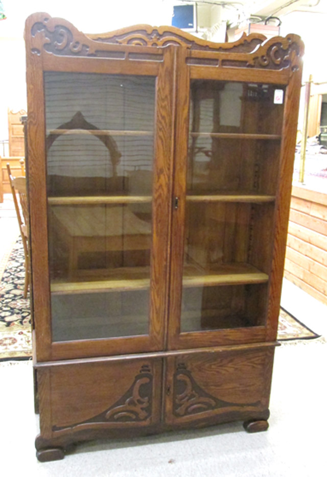 Appraisal: CARVED OAK CABINET BOOKCASE American c having wood shelves behind