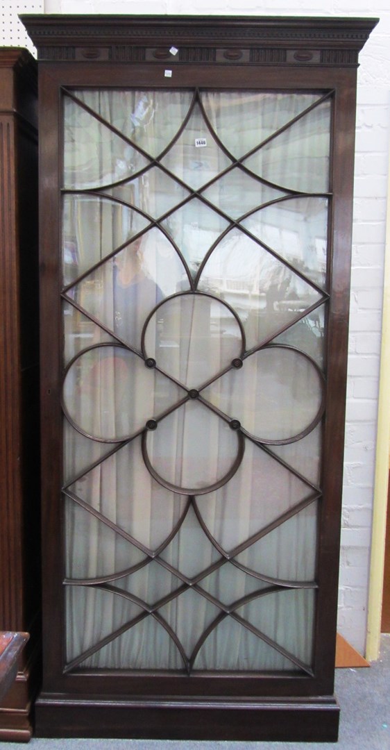 Appraisal: A mahogany bookcase projecting carved cornice above quatrefoil astragal glazed