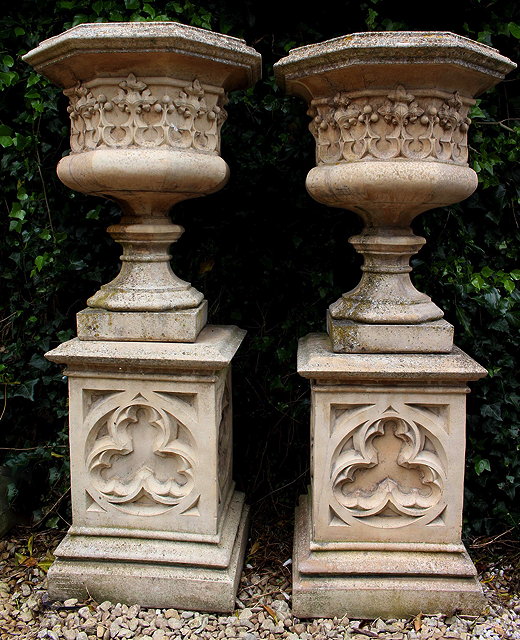 Appraisal: A PAIR OF GOTHIC COMPOSITE STONE URNS on plinths after