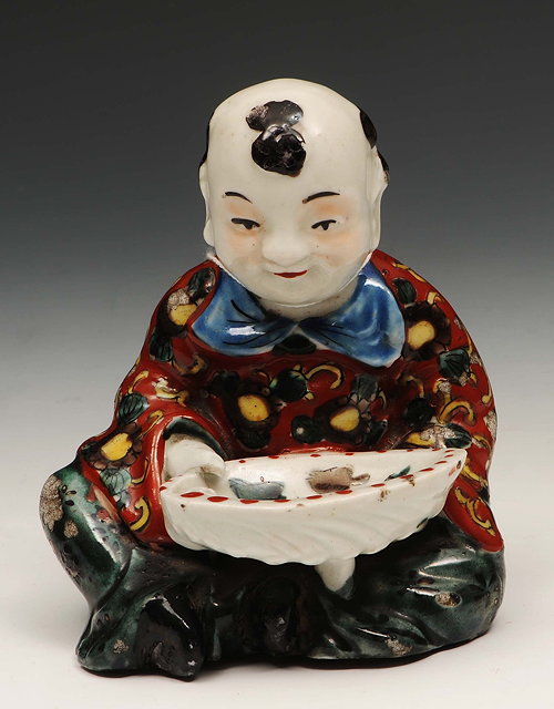 Appraisal: A Japanese Arita model of a seated boylate th Centuryholding