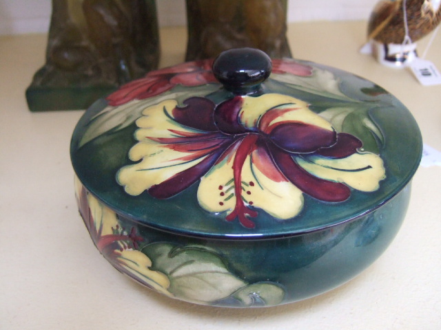 Appraisal: A Moorcroft lidded bowl decorated with hibiscus against a green