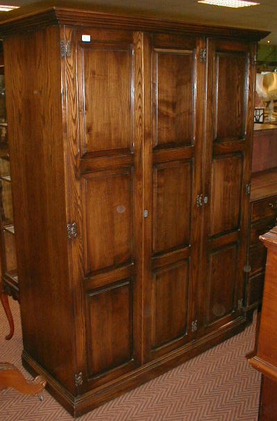 Appraisal: A reproduction triple wardrobe with fielded panel doors