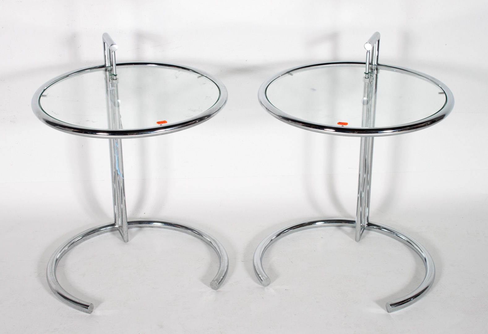 Appraisal: Pr chrome and glass adjustable side tables Eileen Gray design