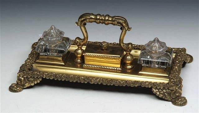 Appraisal: A VICTORIAN CAST BRASS DESK STAND with two square inkwells