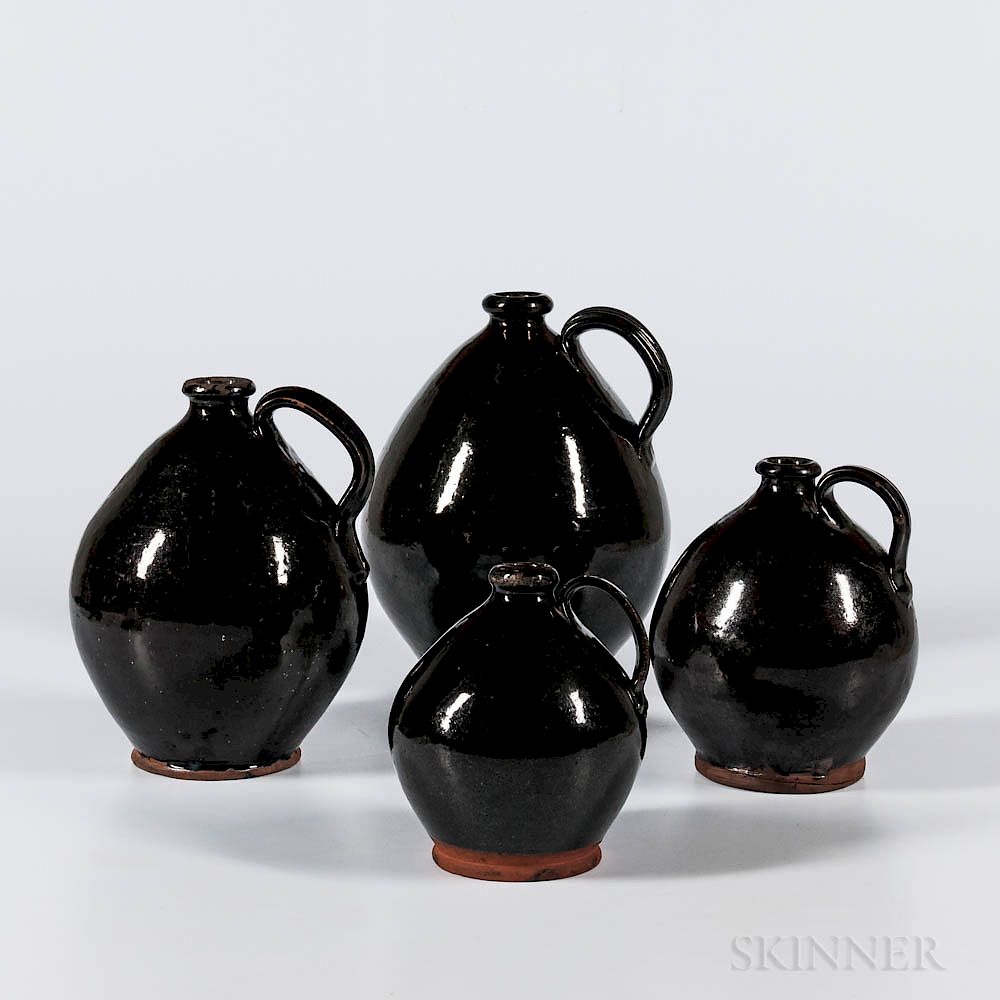 Appraisal: Four Black-glazed Graduated Jugs Four Black-glazed Graduated Jugs North Shore