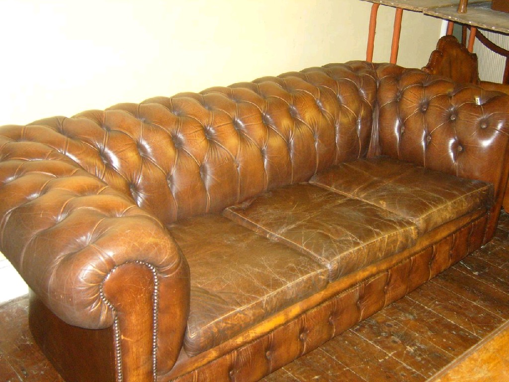 Appraisal: A brown leather upholstered -seat Chesterfield sofa with buttoned back