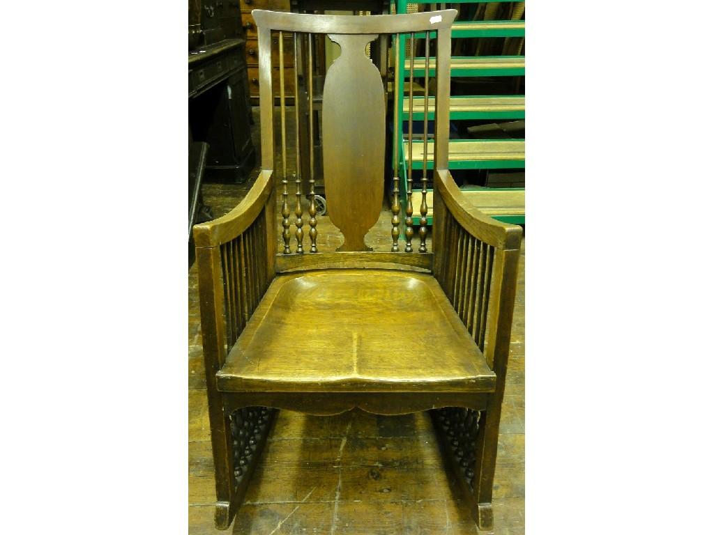 Appraisal: An Edwardian oak rocking chair with slender turned spindle panelled