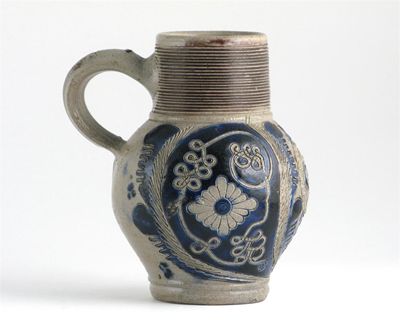 Appraisal: A stoneware jug with sgraffito decoration of large flowers between