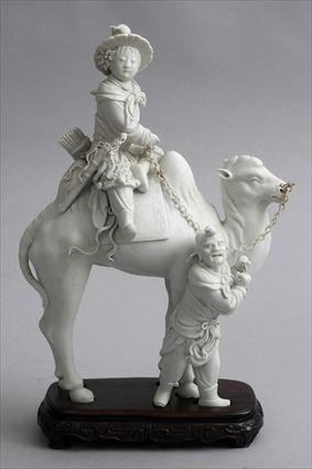 Appraisal: CHINESE BISQUE PORCELAIN CAMEL GROUP Modeled as a child seated