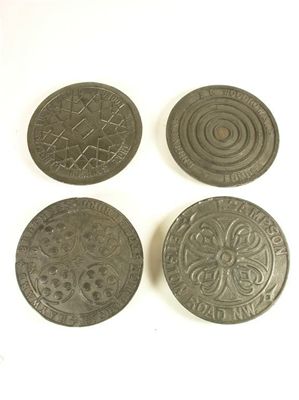 Appraisal: Four cast iron coal hole covers with differing designed tops