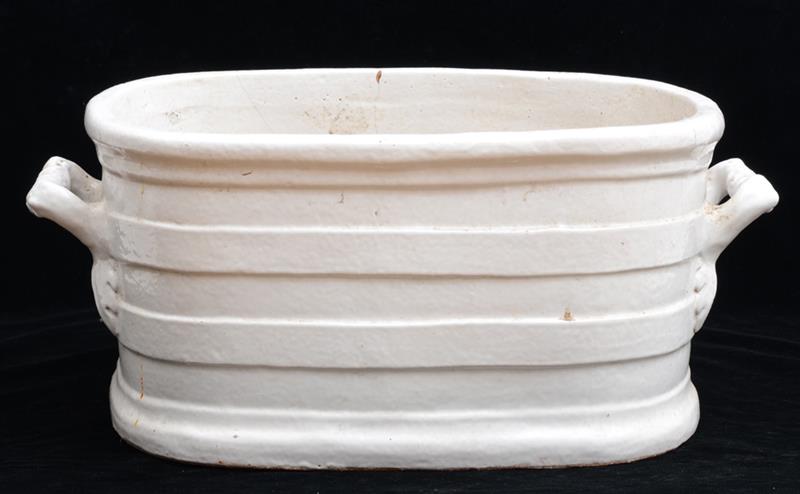 Appraisal: CONTINENTAL IVORY-GLAZED POTTERY TWO-HANDLED TUB The oval bowl with raised