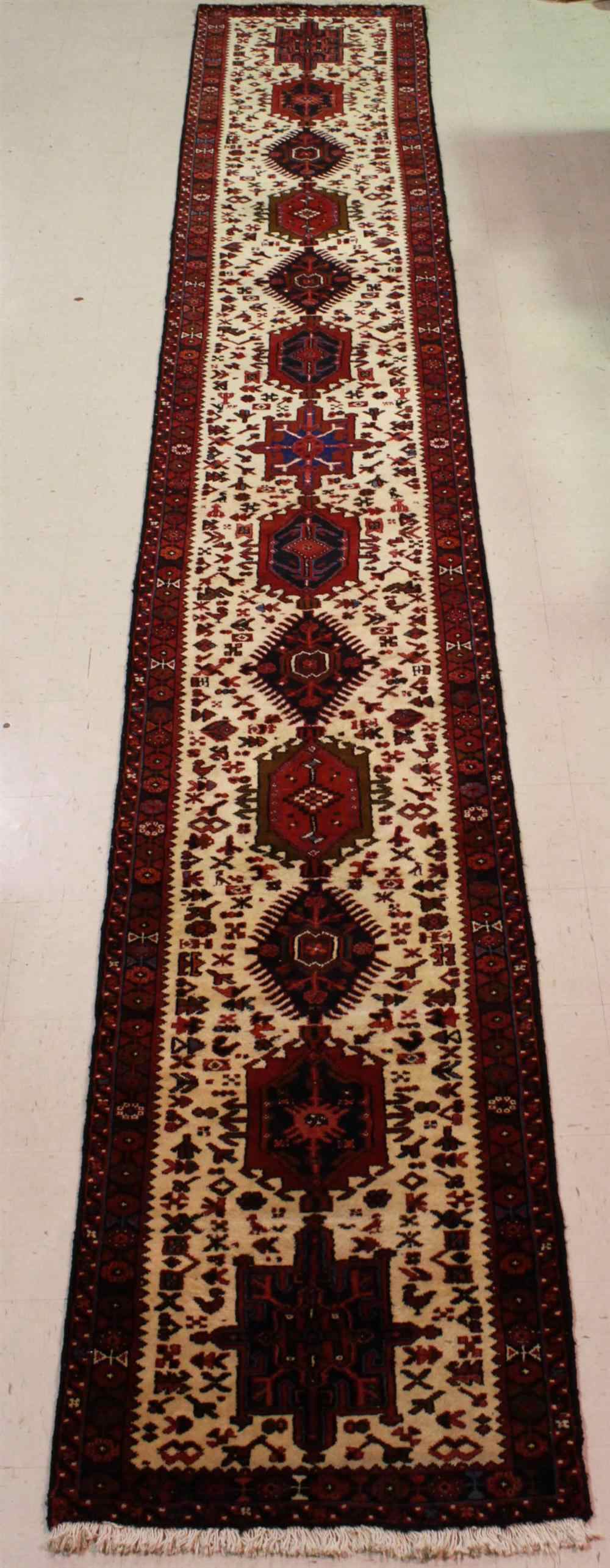 Appraisal: GHARAJEH MEDALLIONS RUNNER RUG Iranian red cream field and black