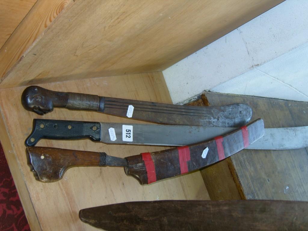 Appraisal: A collection of three various machetes one with carved head