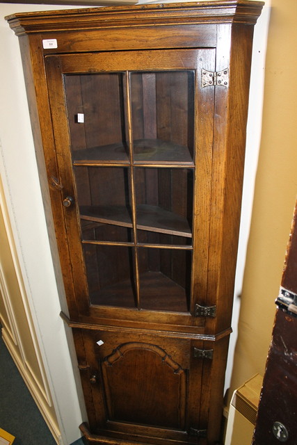 Appraisal: AN OAK REPRODUCTION CORNER CUPBOARD the interior fitted shelves enclosed