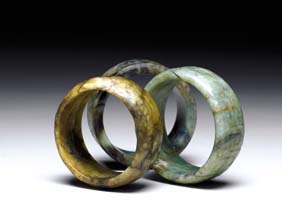 Appraisal: THREE JADE AND HARDSTONE BANGLES Three Chinese carved jade and