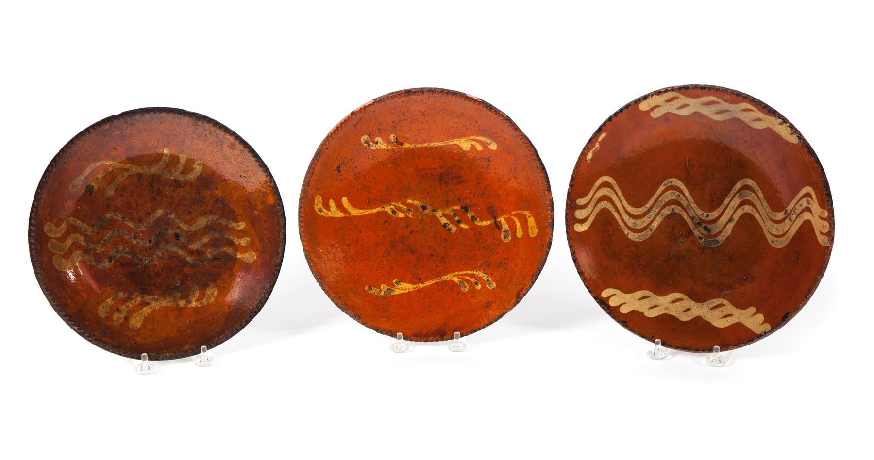 Appraisal: THREE REDWARE PLATES WITH COGGLED RIMS AND YELLOW SLIP DECORATION