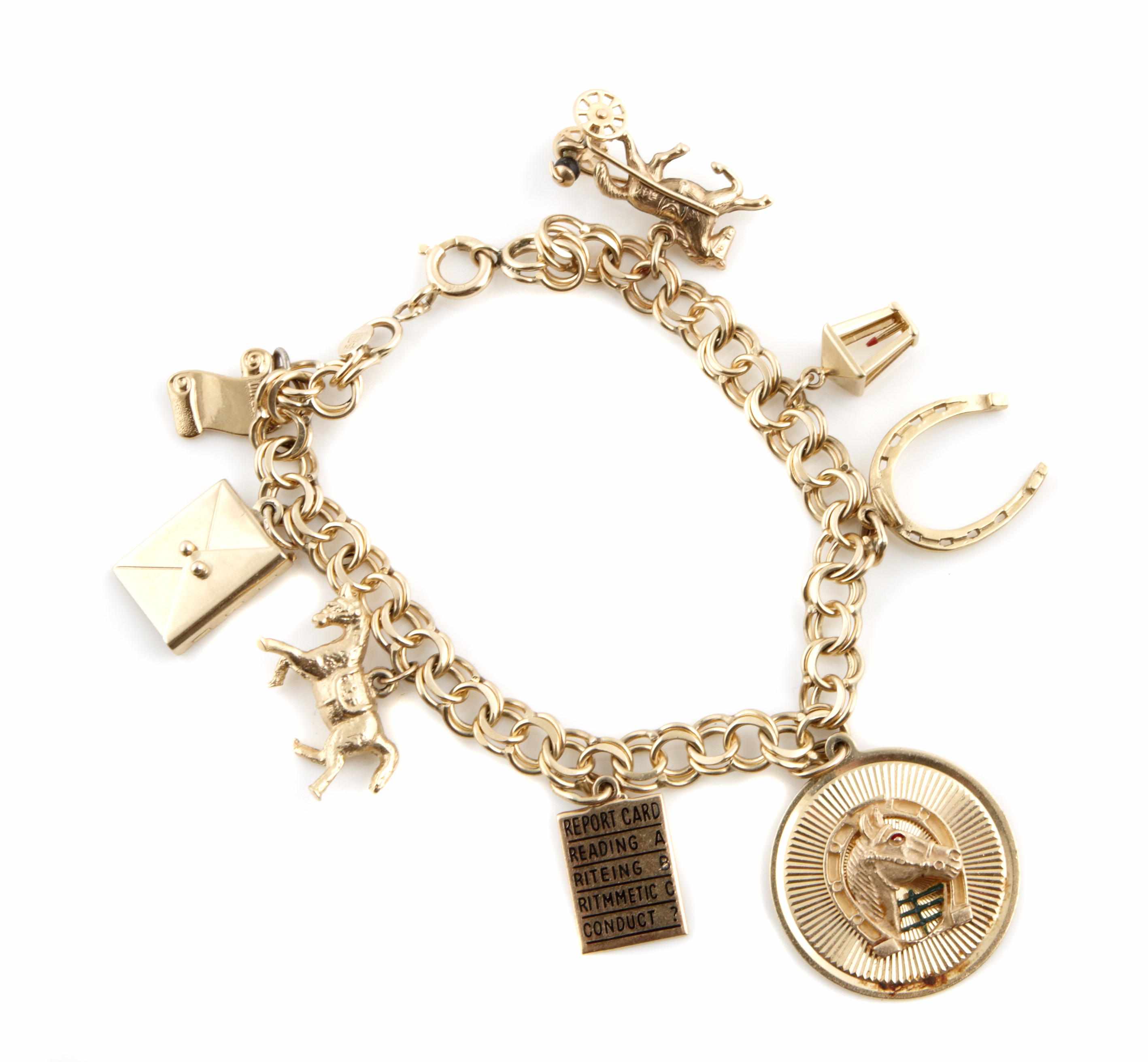 Appraisal: A gold charm bracelet including charms of horses a scroll