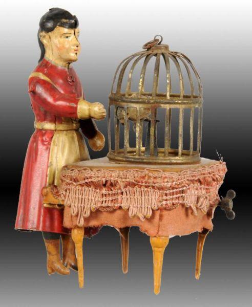 Appraisal: German Hand-Painted Tin Woman with Birdcage Toy Description Wind-up working