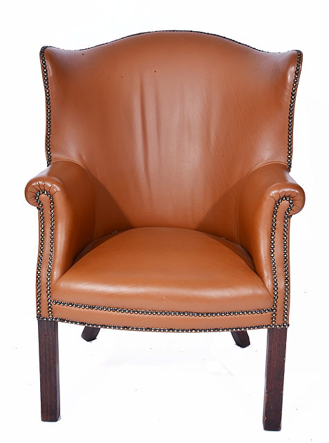 Appraisal: A BROWN LEATHER UPHOLSTERED WING BACK ARMCHAIR with curving back